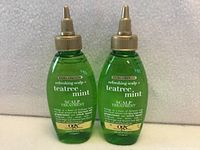 Front view of two OGX Teatree Mint scalp treatment bottles