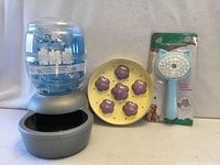 Front view of waterer, feeder dish front, grooming brush package front