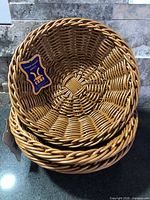 Stack of three honey brown woven-look baskets with tag visible