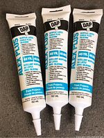 Three sealed DAP Alex Plus caulk tubes front view