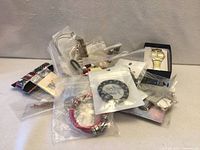 Pile of bagged jewelry with wristwatch and various bracelets visible
