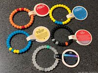 Seven beaded bracelets with hang tags displayed on countertop