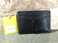 Front view of black Marc Jacobs card holder with tag attached