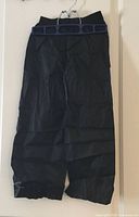 Front view of black kids waterproof overtrousers on hanger
