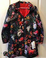 Floral side of reversible coat hanging, buttons, collar, pockets visible with tag attached