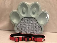 Paw-shaped feeding dish and red-pink dog collar in front