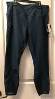 Front view of teal RBX 7/8 leggings on hanger showing full length and waistband tag