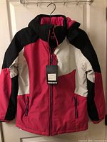 Front view of pink/white/black Smonty ski jacket on hanger with tags attached