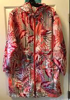 Front view of Spanner floral spring coat hanging on door, showing zipper, hood and pattern