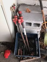 Two red pipe clamps in crate beside cinder blocks