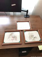 All three framed artworks on desk