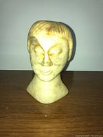 Front view of carved stone female head bust