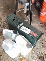 Coleman stove with three white jugs beside it