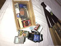 Cardboard box with mixed trading card stacks, sleeves and deck boxes visible