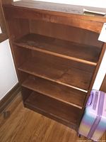 Front view of wooden bookcase showing four shelves and finish wear