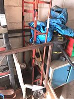 Full view of red steel hand truck among other items
