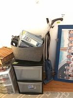 All items stacked together: storage drawers, felt bin holding sheet set, vacuum alongside