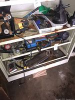 Three shelves with drill, funnels, angle grinder, floor jack, socket tray