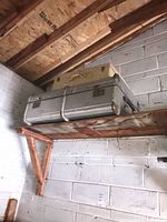 Two vintage suitcases on garage shelf, silver trunk bottom, beige suitcase top