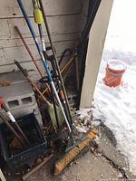 Group of garden tools, crate and cinder blocks in garage corner