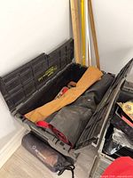 Open black plastic tote showing rolled mats and straps inside