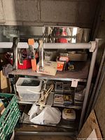 Shelving unit with clamps, red bin of fasteners, metal organizer, various boxes