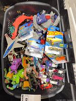 Basket filled with assorted loose cars, figures and packaged Hot Wheels