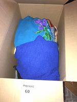 Box showing turquoise floral top and royal blue knit garment