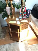 Full view of octagonal honey oak veneer side table with items on top