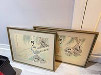 both framed prints leaning against wall