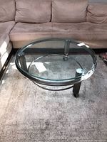 Full view of round glass coffee table situated by sectional sofa