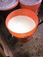 Open orange bucket showing white cement powder inside