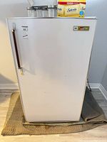 front view of white upright freezer with chrome handle and Kmart badge