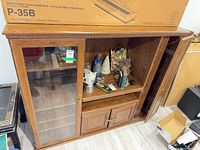 Front view of cabinet showing glass door, open shelves, lower doors and side cabinet