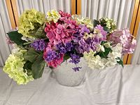 Front view of full artificial arrangement showing variety of flower types and colors in galvanized bucket