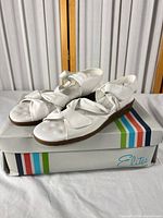 Pair of white leather wedge sandals on Elites box