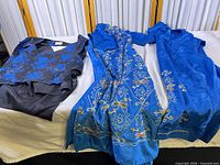All three garments laid flat: floral vest, embroidered pants, cobalt tunic