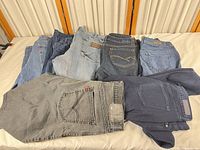 Stack of eight jeans showing variety of colors and brands