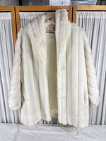 Front view of ivory faux-fur coat on hanger