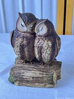 Front view of two owl ceramic music box on log