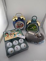 Lot overview showing both clocks, boxed golf balls, ceramic whale bank