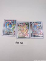 Three sleeved VMAX cards laid out side by side