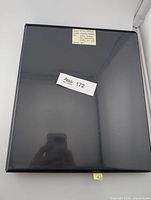 Closed black binder showing lot tag