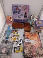 All items laid out: notebook, lanyard, sticker sheets, round stickers, GX sticker, Charizard sticker, acrylic standee sheet, mini tin, jewelry tin, Slowpoke figure box