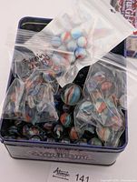 tin containing several bags and loose marbles