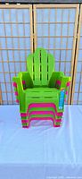 Front view of six stacked green and pink kids Adirondack chairs