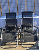 Front view of both matching reclining lounge chairs showing mesh seats, frames, and headrests