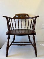 Front view of Windsor armchair showing saddle seat, spindles and fleur-de-lys back cutouts