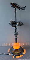 Full view of illuminated chrome airplane ashtray lamp stand