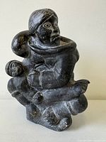 Front view of artist signed Inuit soapstone sculpture showing adult figure carrying child